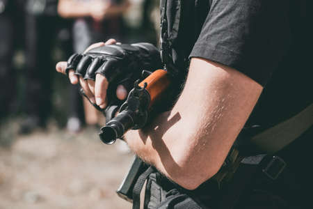 The soldier in the performance of tasks in camouflage and protective gloves holding a gun. War Zone.の写真素材