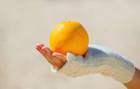 The girl in white gloves holding a ripe orange orange. Dropping e overweight.の写真素材