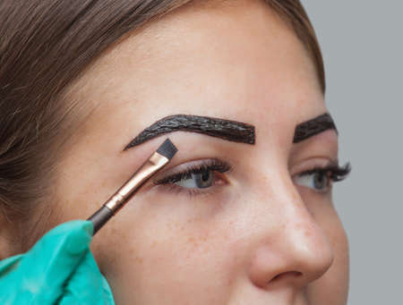 makeup artist applies paint henna on previously plucked, design, trimmed eyebrows in a beauty salon in the session correction. Professional care for face.の写真素材