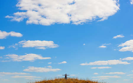 Man tourist is standing on top of a mountain with open hands to the sky.の写真素材