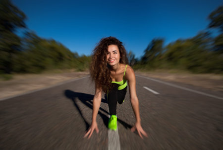 Attractive curly girl athlete doing morning exercises outside. The concept of sports and healthy...