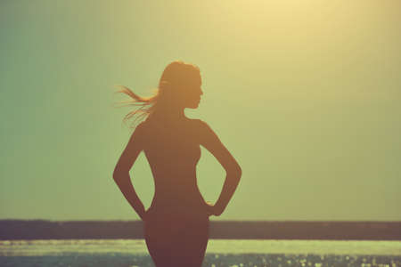 Silhouette of a beautiful, slim girl on a background of a sunset on the beach.の写真素材