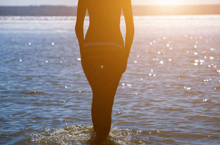 Silhouette of a beautiful, slender girl on the background of sunset by the sea on the beach.の写真素材