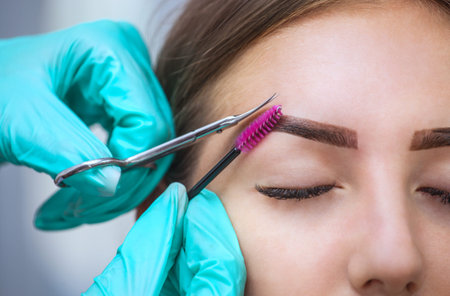 Master makeup corrects, gives shape to and cut with scissors previously painted with henna eyebrows...