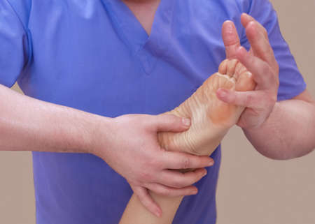 The doctor-podiatrist does an examination and massage of the patient's foot in the clinic.の写真素材