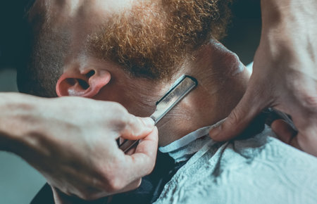 A hairdresser makes a man a haircut of his beard, and a mustache in a barbershop.