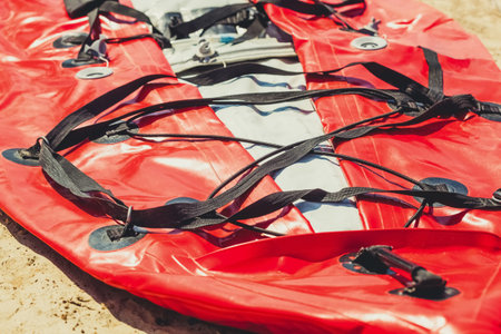Not inflated red kayaking lies on the river bank.の写真素材