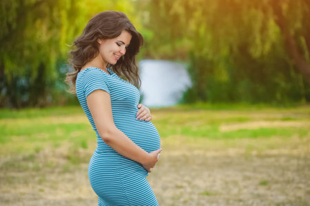 Adult, beautiful pregnant woman  in the park on a lake background.