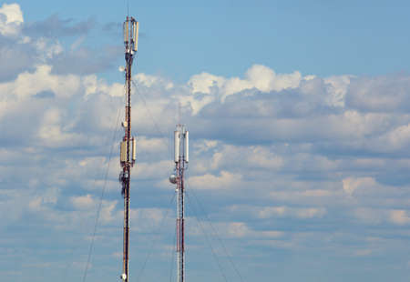 Two towers of cellular communication on the background of a blue, cloudy sky.の写真素材
