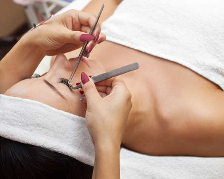 Eyelash removal procedure close up. Beautiful Woman with long lashes in a beauty salon. Eyelash extension.の写真素材