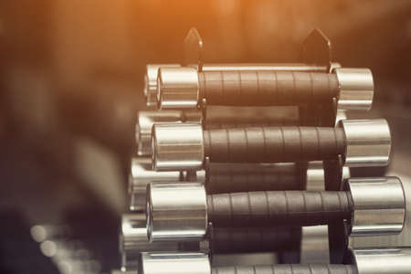 Metal dumbbells on an iron stand in a sports hall, close-up on a black background. Sports concept, fat burning and healthy lifestyle.の写真素材