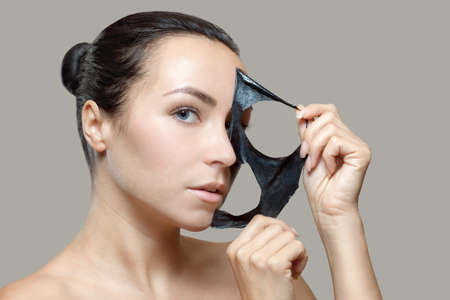 a black mask to the face of a beautiful woman. Spa treatments and care of the cats in the beauty salon.の写真素材