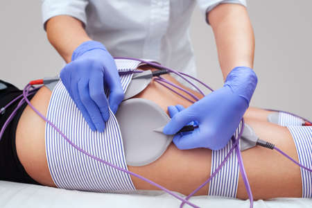 The procedure of myostimulation on the legs and buttocks of a woman in a beauty salon. Caring for the body, reducing excess weight.の写真素材