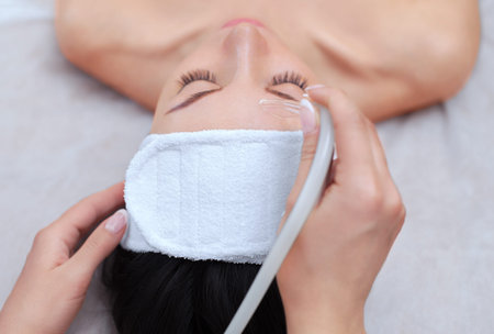 The cosmetologist makes the procedure vacuum face cleaning of a beautiful, young woman in a beauty...