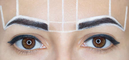 Permanent make-up for eyebrows of beautiful woman with thick brows in beauty salon. Closeup beautician doing  tattooing eyebrow.の写真素材