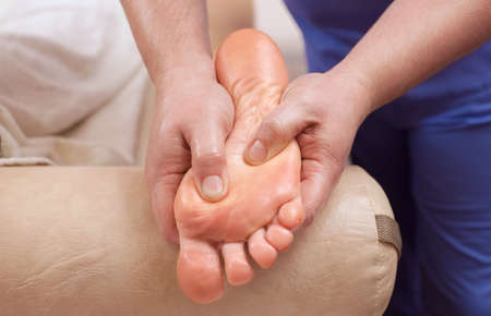 The doctor-podiatrist does an examination and massage of the patient's foot in the clinic.