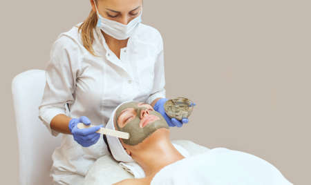 The procedure for applying a mask from clay to the face of a beautiful woman. Spa treatments and care of the cats in the beauty salon.の写真素材