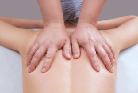 The masseur makes a massage on the back of the patient in the beauty salon. Medical care for the...