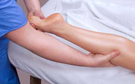 The doctor-podiatrist does an examination and massage of the patient's foot in the clinic.の写真素材