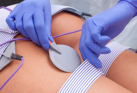 The procedure of myostimulation on the legs and buttocks of a woman in a beauty salon. Caring for the body, reducing excess weight.の写真素材