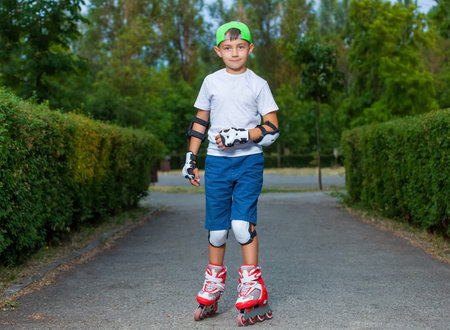 A little boy goes rollerblading in the summer in the park.の写真素材