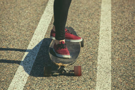 A girl is riding a longboard on the asphalt, legs close-up.の写真素材