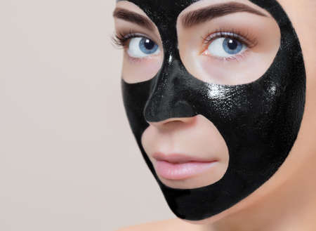 Facial black Mask  to the face of a beautiful woman. Spa treatments and care of the cats in the beauty salon.の写真素材