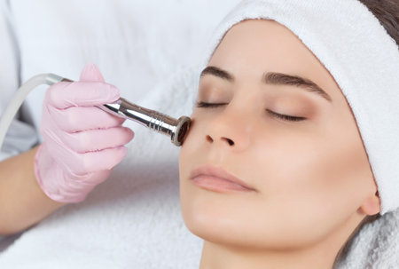 The cosmetologist makes the procedure Microdermabrasion of the facial skin of a beautiful, young...