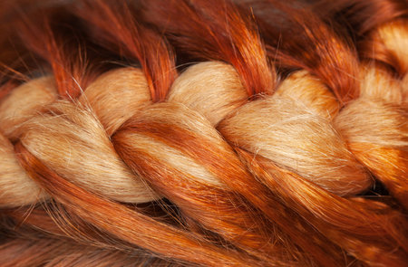 Beautiful, healthy, long, curly, red hair close-up. Braiding. Professional hair care.