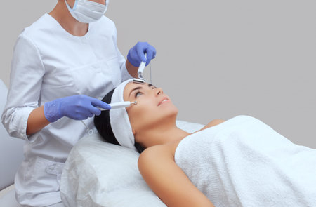 The cosmetologist makes the apparatus a procedure of Microcurrent therapy of a beautiful, young...