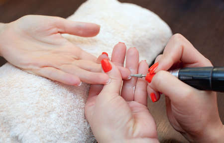 The master of the manicure saws and attaches a nail shape during the procedure of nail extensions with gel in the beauty salon. Professional care for hands.の写真素材