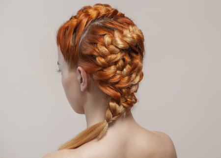 Beautiful, with long, red-haired hairy girl, hairdresser weaves a  braid, close-up in a beauty...