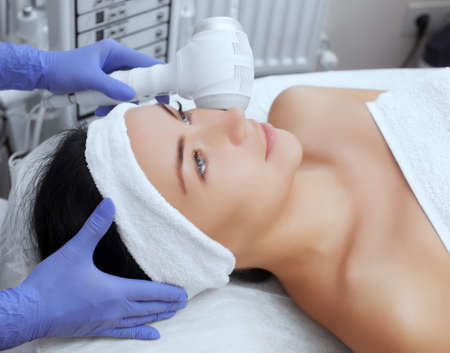 The doctor-cosmetologist makes the procedure Cryotherapy of the facial skin of a beautiful, young woman in a beauty salon.Cosmetology and professional skin care.の写真素材