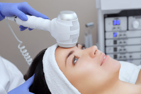 The doctor-cosmetologist makes the Cryotherapy procedure of the facial skin of a beautiful, young...