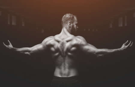 Silhouette of a slender bodybuilder doing sports in the gym.の写真素材