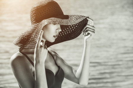 Attractive girl in a black hat worn on the head, on the beach. Photo black and whiteの写真素材