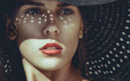 Portrait of a beautiful woman in a black beach hat on holiday by the sea.の写真素材