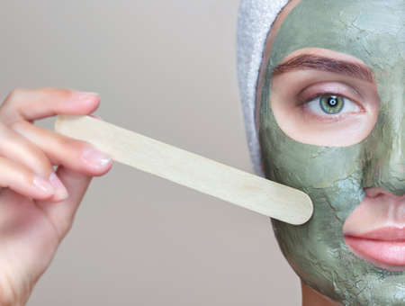 The procedure for applying a mask from clay to the face of a beautiful woman. Spa treatments and care of the face in the beauty salon.の写真素材