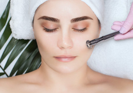 The cosmetologist makes the procedure Microdermabrasion of the facial skin of a beautiful, young...