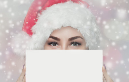 Portrait of a beautiful woman in a red  Santa Claus hat and knitted red sweater holds in her hand a...