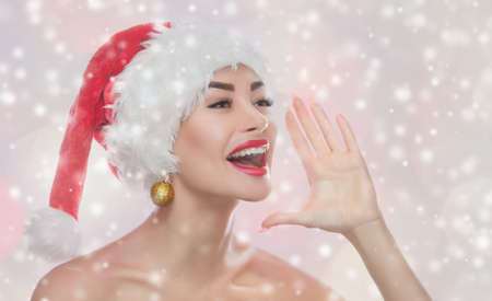 Portrait of a beautiful woman in a red  Santa Claus hat on snowflakes background. New Year's concept.の写真素材