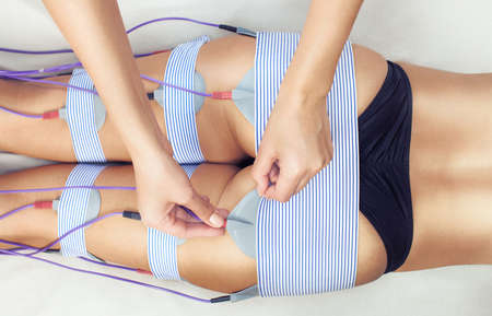 The procedure of myostimulation on the legs and buttocks of a woman in a beauty salon. Caring for the body, reducing excess weight.の写真素材