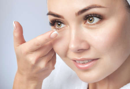 One woman holds contact lens on her finger. Eye care and the choice between the means to improve vision.の写真素材