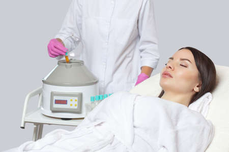 Cosmetologist does prp therapy on the face of a beautiful woman in a beauty salon. There is in vitro  blood plasma, ready for injection. Cosmetology concept.の写真素材