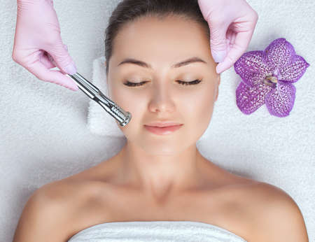 The cosmetologist makes the procedure Microdermabrasion of the face skin of a beautiful woman in a beauty salon.Cosmetology and professional skin care.の写真素材