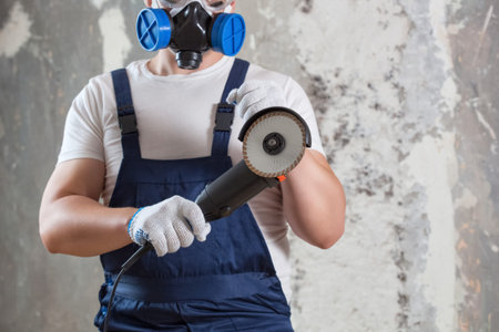 The builder holds in hands Angle grinder. Repair work, interior decoration of walls.