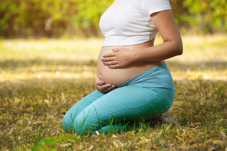 Adult pregnant woman in the park on the lawn. 9 months of pregnancy and childbirth.の写真素材