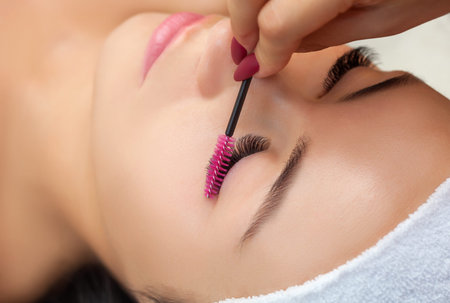 Eyelash extension procedure close up. Beautiful woman with long eyelashes in a beauty salon. Women's...
