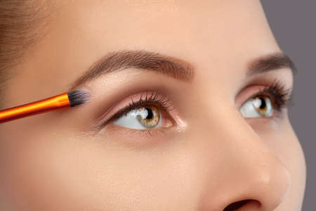 Make-up artist does eyebrow make-up to a woman. Beautiful thick eyebrows close up. Professional makeup and cosmetology skin care.の写真素材
