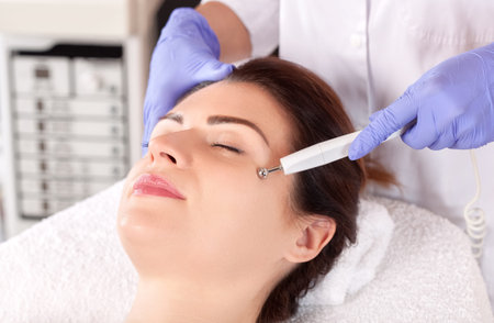 The cosmetologist makes the apparatus procedure of Microcurrent therapy for a beautiful, young woman...